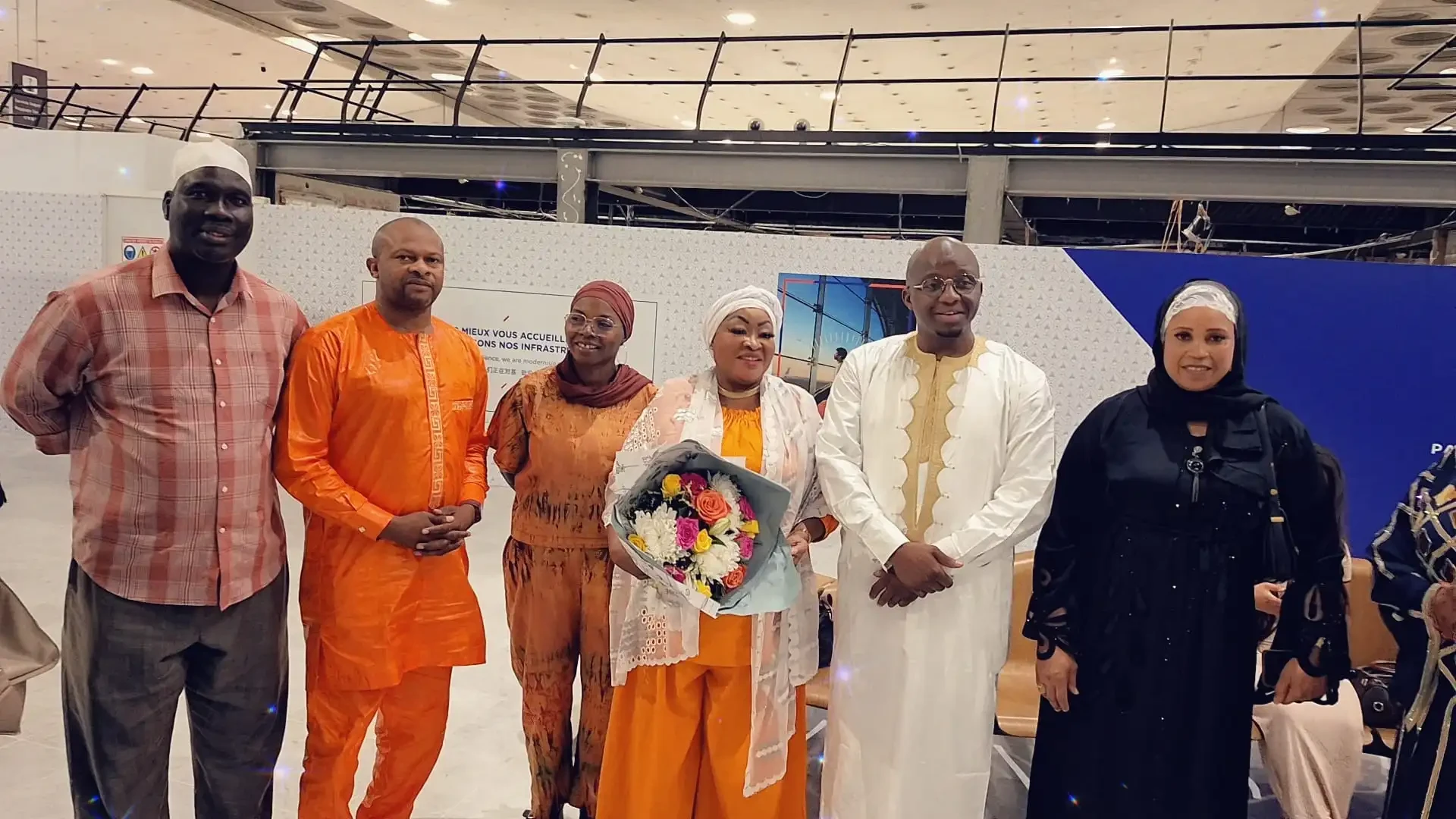 Accueil des pèlerins de la diaspora à Paris : un groupe pose autour d’un bouquet de fleurs